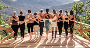 Rear view of a group of slim body-positive sportive active friendly women doing fitness and yoga together among mountain ecologically clean nature. Ecological Sports Tourism Concept