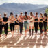 Rear view of a group of slim body-positive sportive active friendly women doing fitness and yoga together among mountain ecologically clean nature. Ecological Sports Tourism Concept